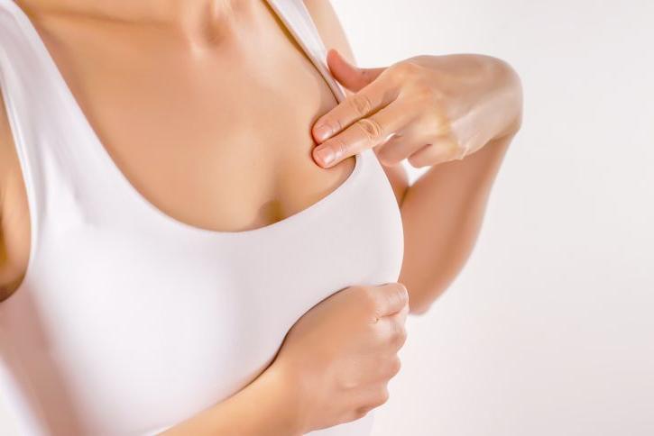 Woman in tank top examining her breast